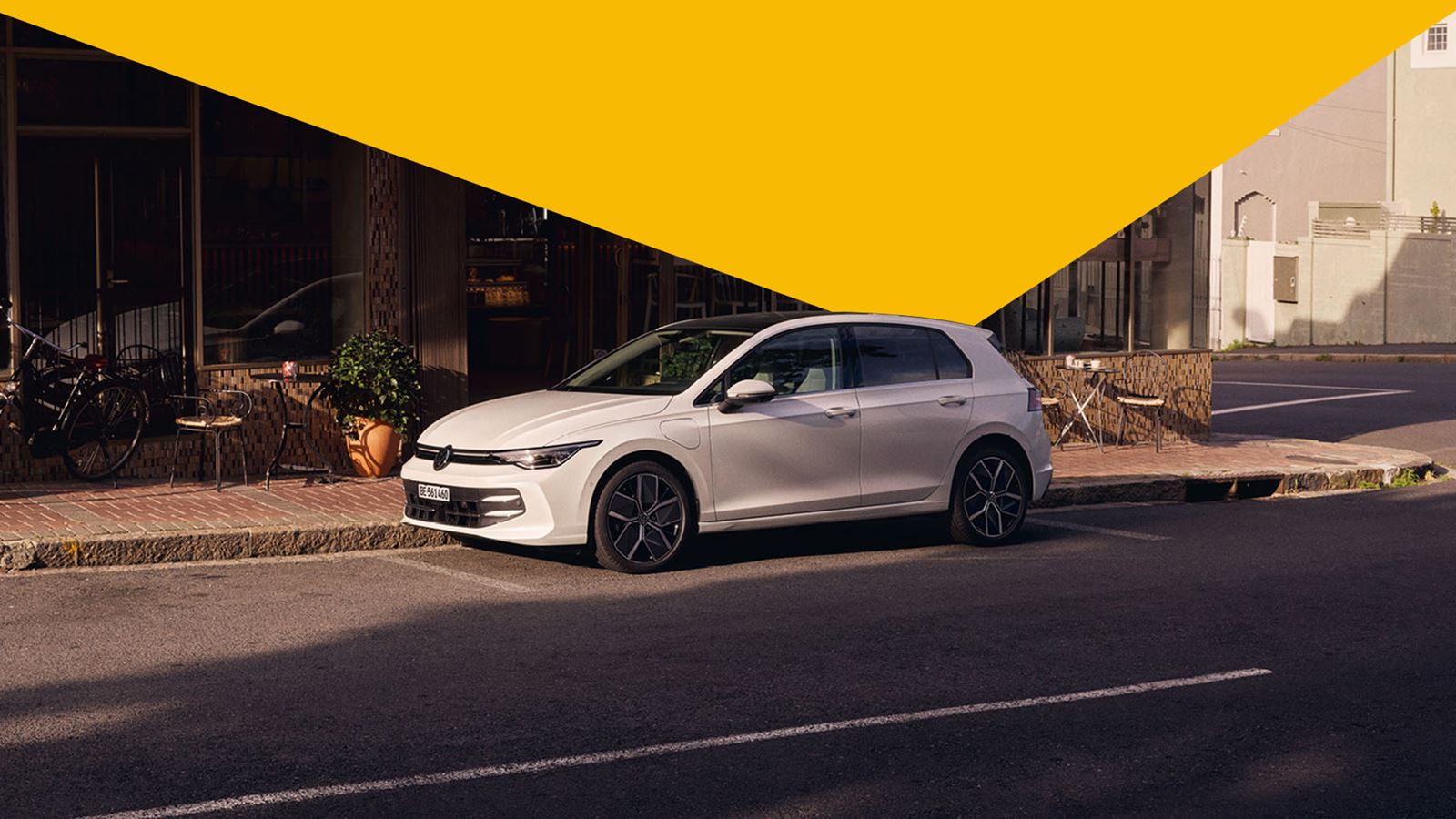 Der Golf von Volkswagen vor einem Gebäude (mit gelbem Designelement-Dreieck oberhalb)