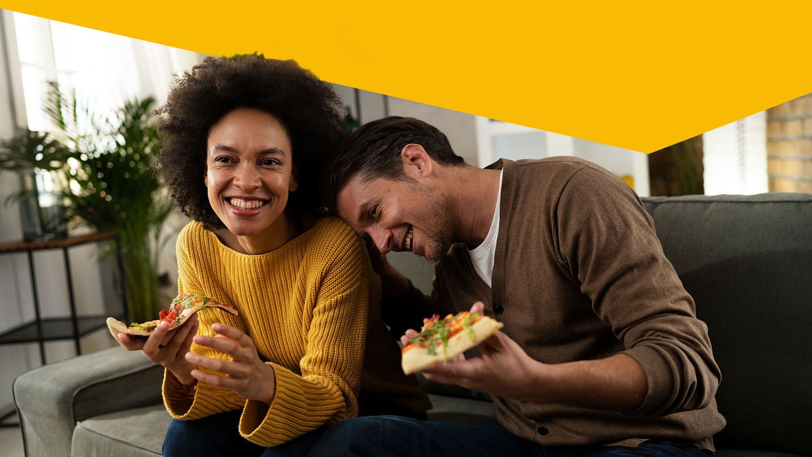 Deux personnes mangent ensemble une pizza sur le canapé (avec un élément de design jaune superposé)