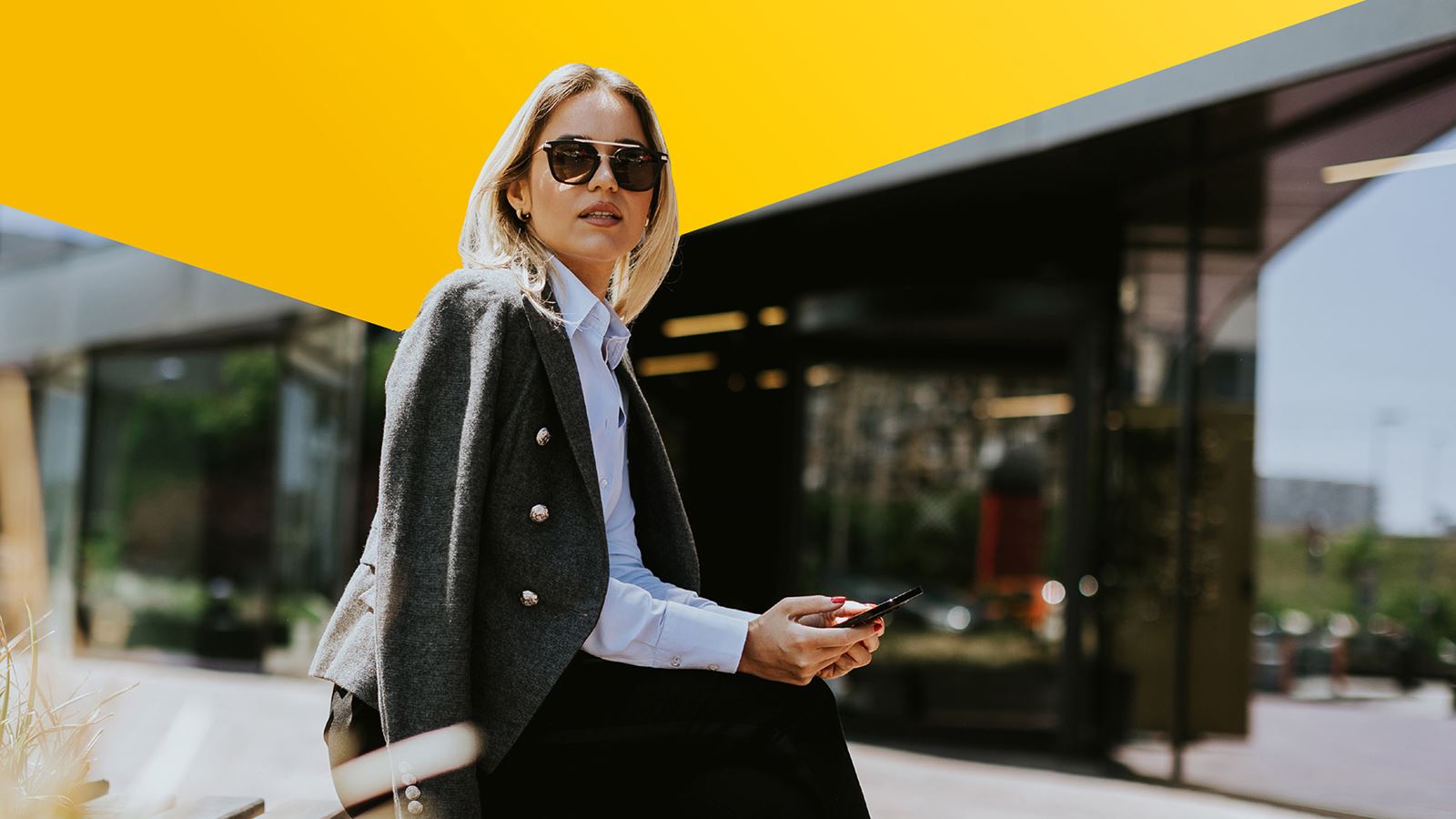 Une femme est assise au soleil avec des lunettes de soleil (avec un élément de design jaune au-dessus)