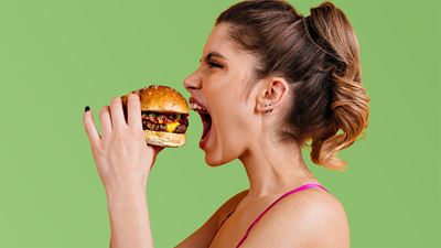 Une jeune femme mord avec impatience dans un succulent burger