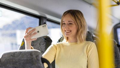 Eine Frau schaut lächend in ihr Smartphone