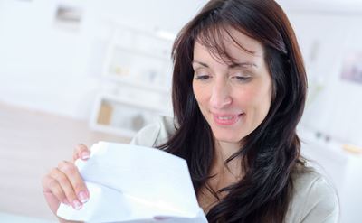 Une femme ouvre un publipostage en souriant